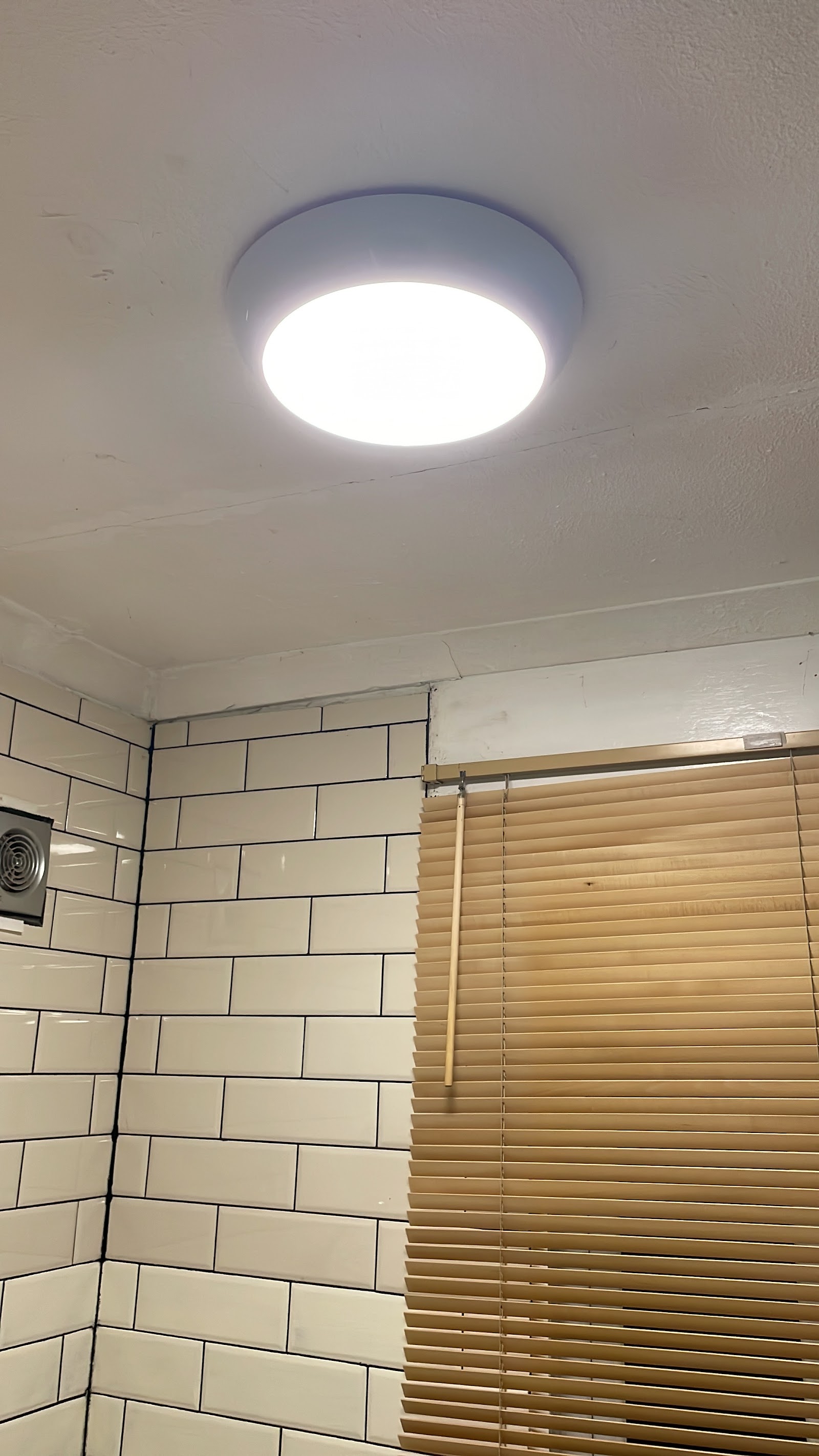 Bathroom ceiling light and extractor fan installed cleanly against fresh tiling.