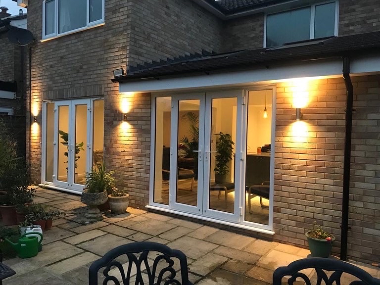 Rear extension lit up at dusk — wall lights and internal lighting on a completed renovation.