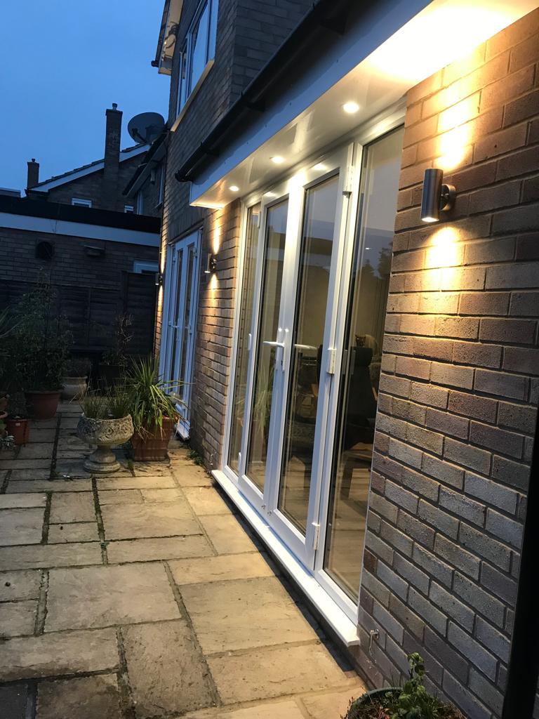Exterior wall lights and downlights across a rear patio